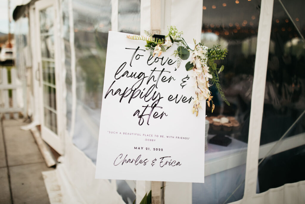 image shows a sign that says to love, laughter, and happily ever after at a wedding