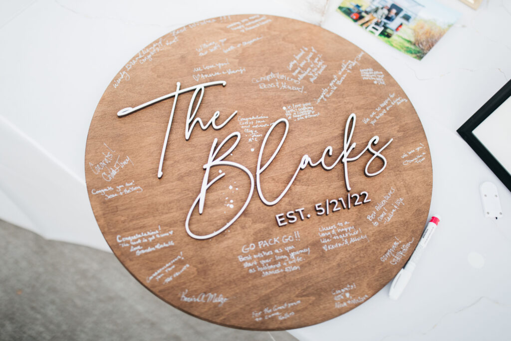 A wedding guest sign featuring the couples name and guest signatures 
