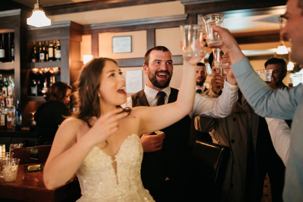 image shows a bride and her friends toasting their drinks in the air