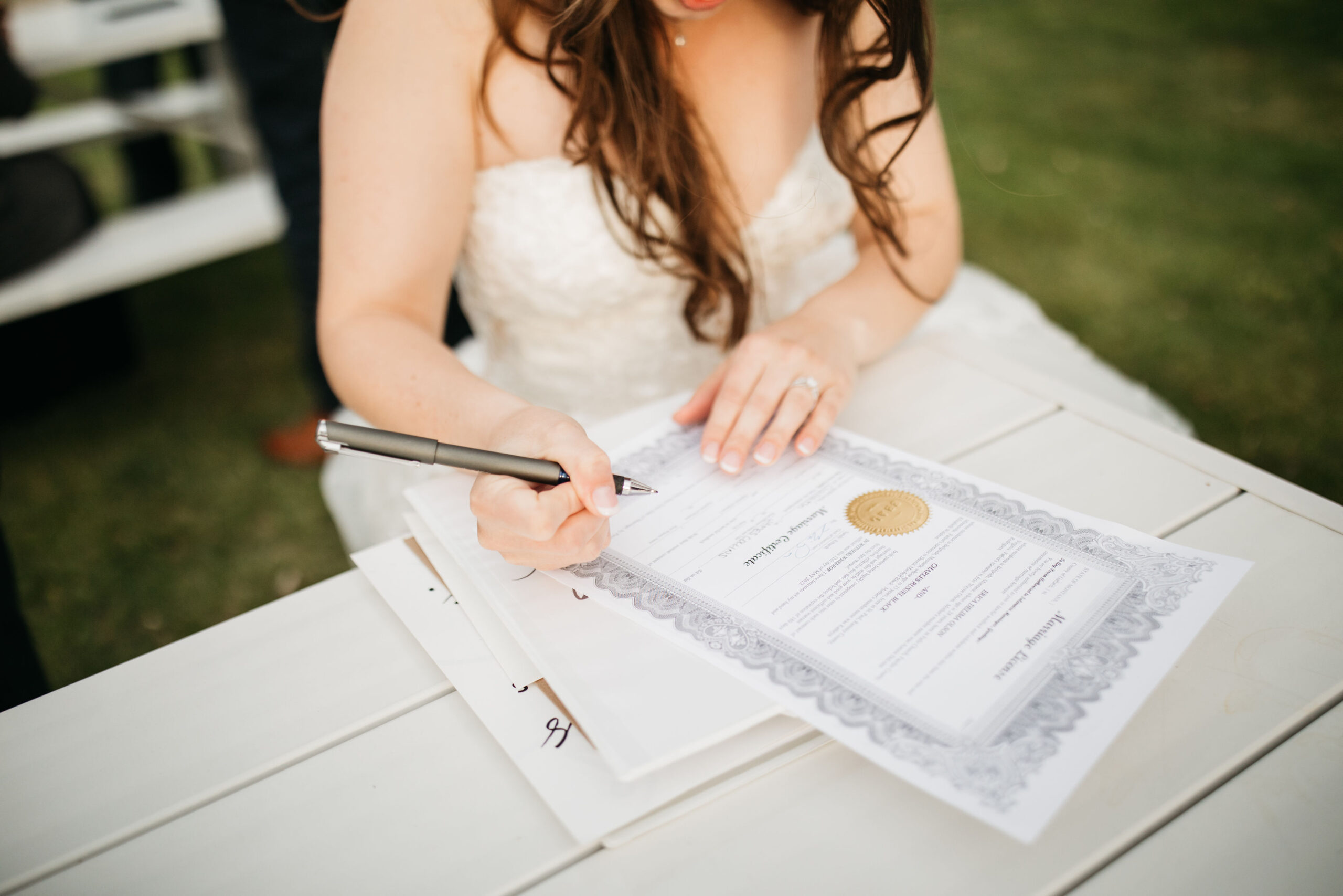 Image shows a bride signing her marriage license
