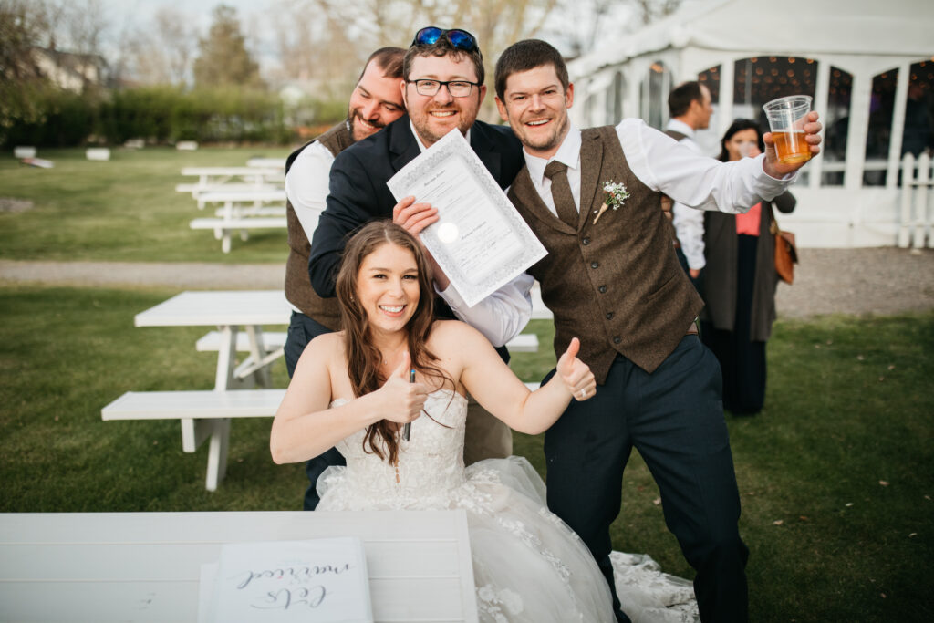 Image shows bride and groom with friends holding the signed marriage license