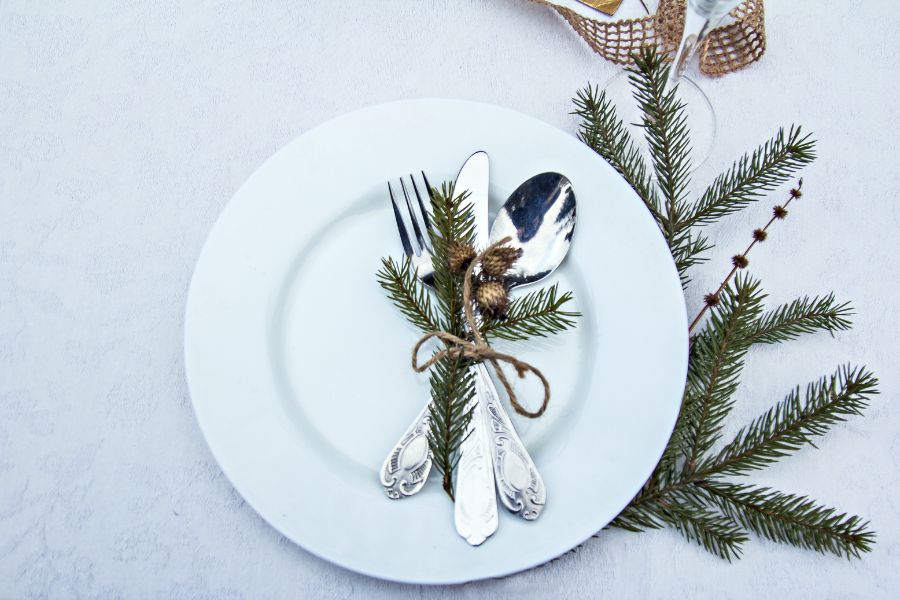 image shows dinnerware set up with winter greenery accents
