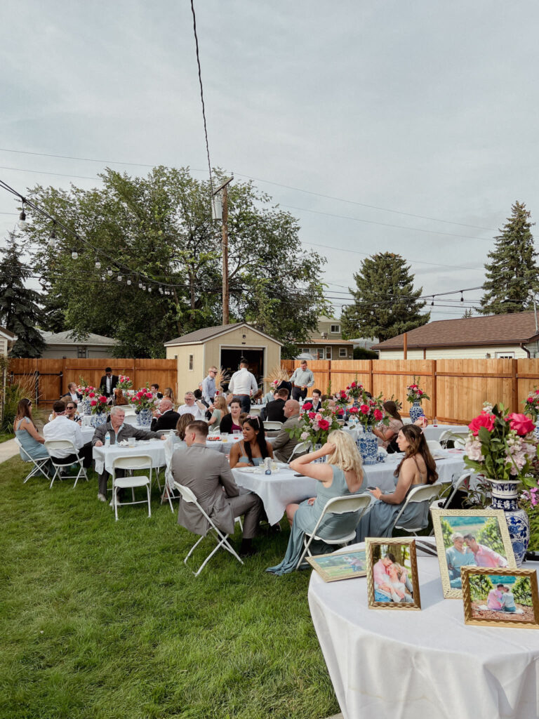 image shows a backyard full of wedding guests enjoying themselves at a backyard wedding reception