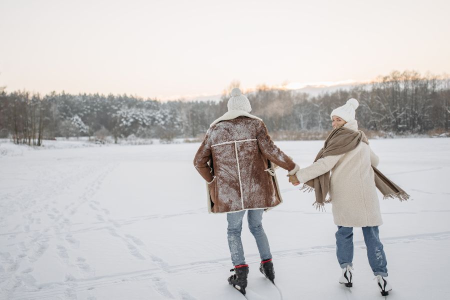 image shows couple holding hands while ice skating