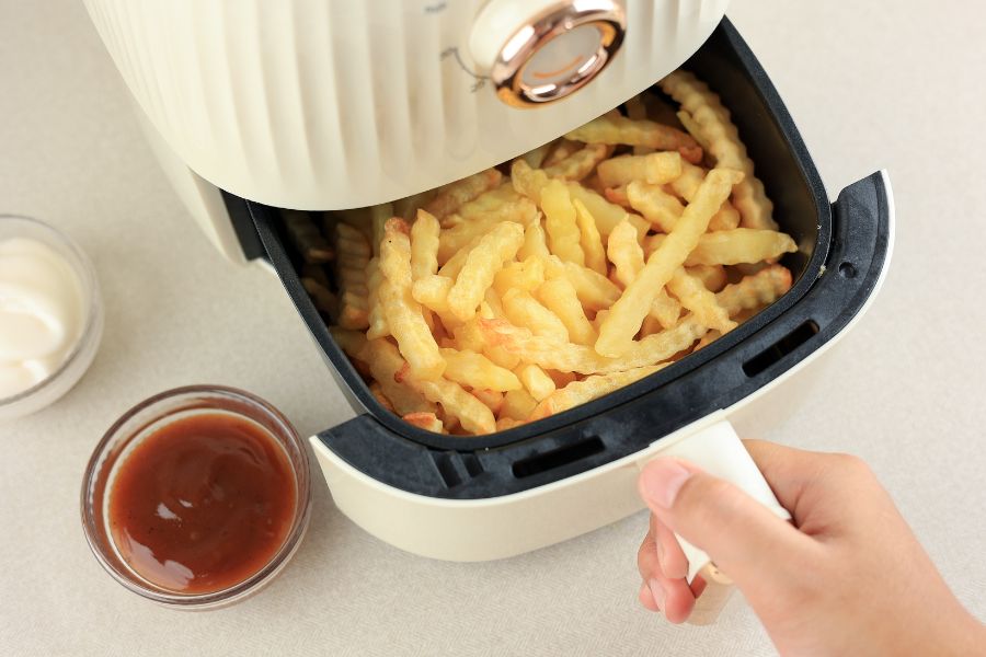 image shows someone opening up an air fryer filled with french fries