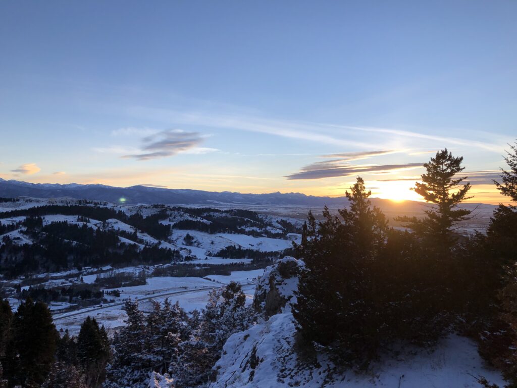 Image shows a snowy mountain sunset