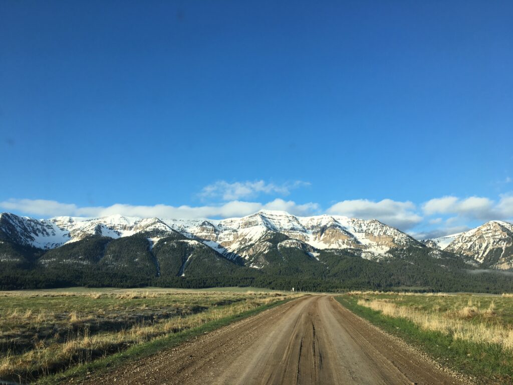 image  shows a dirt road leading to snowy mountains