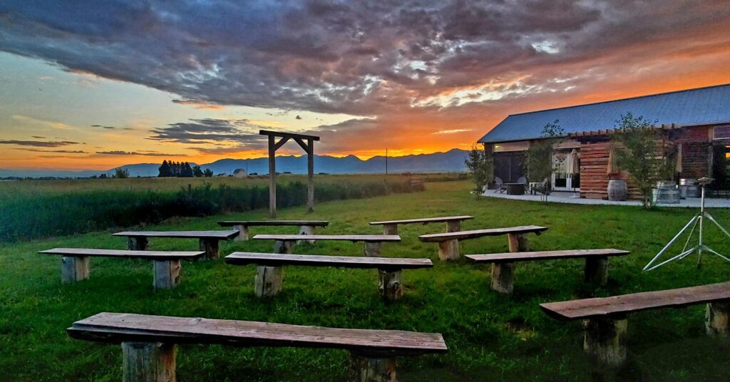 Image shows love lane barn outdoor ceremony area with bench seating, a ceremony arch, and stunning vista of the bridger mountains