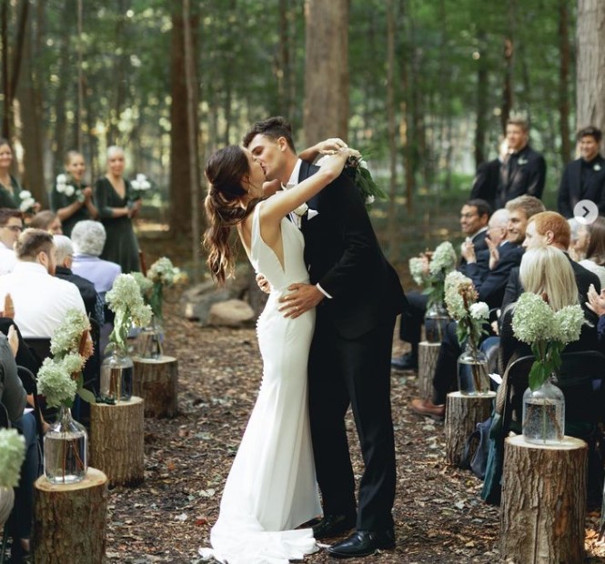 a bride and groom celebrate with a kiss while their guests cheer them on down the aisle.
