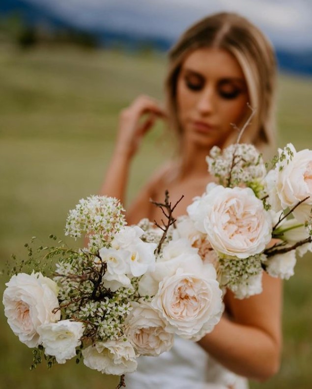 image shows a bride holding an asymmetric floral boquet