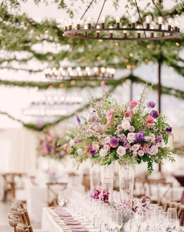 image shows large floral table centerpieces with a canopy of greenery