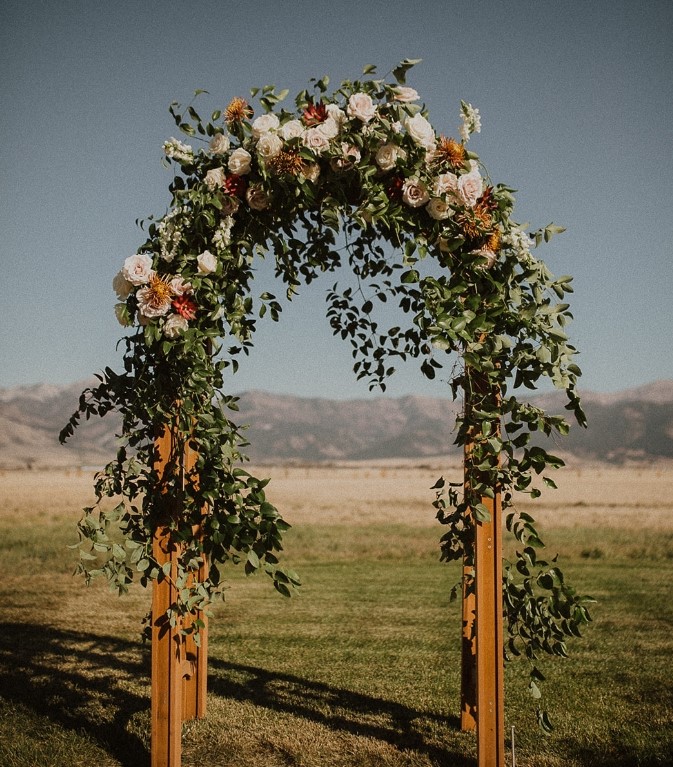 image shows a floral ceremony arch with greenery and flowers