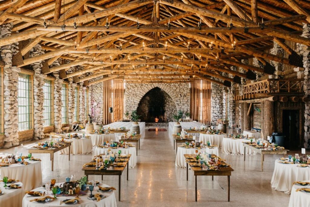 image shows a beautiful and romantic setting for a wedding reception featuring log beams and rock accents
