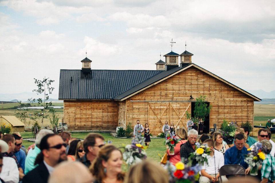 image shows a rustic wedding barn with guests seated for a wedding ceremony