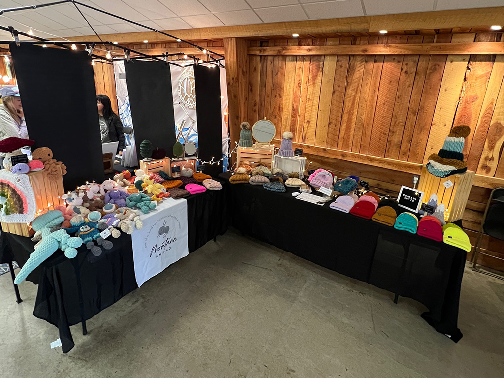 image shows a farmers market booth selling knitted hats and crochet toys