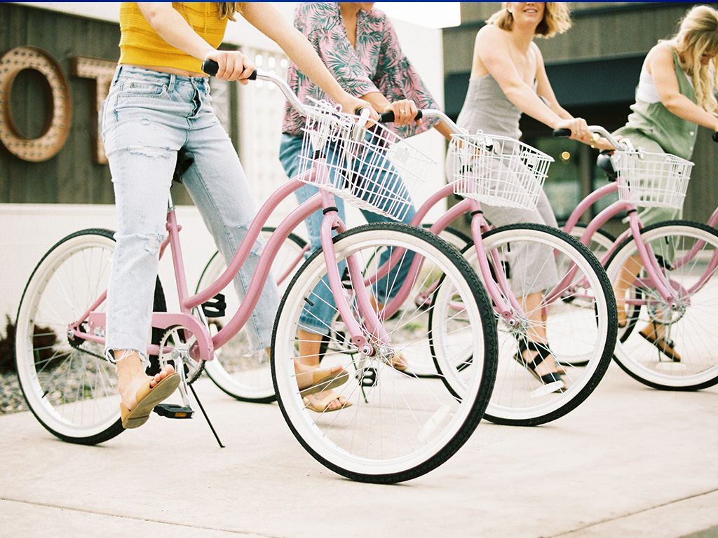 image shows 4 women each riding a pink bicycle 