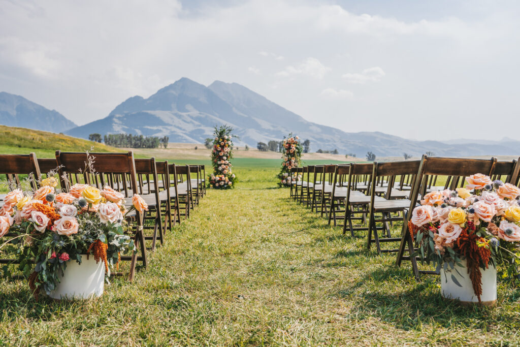 image shows an outdoor wedding ceremony set up against the backdrop of the mountains
