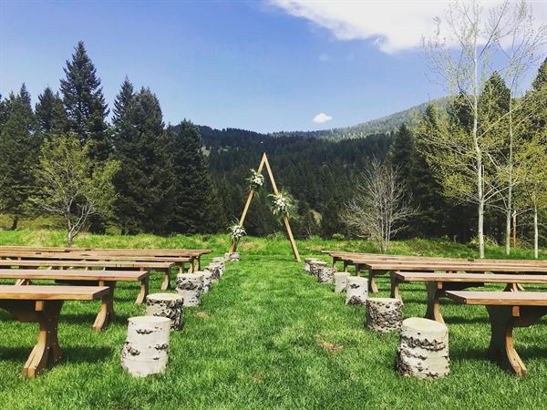 image shows a ceremony location nestled in the mountains of bozeman. Featuring bench seating and an angular ceremony arch