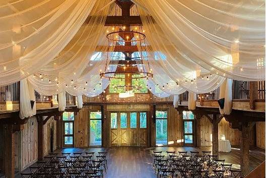 image shows a wedding venue with beautiful ceiling drapery and chairs set up