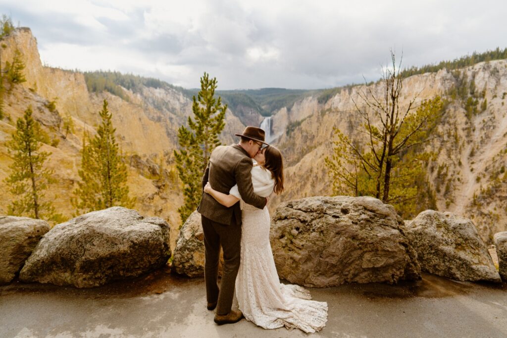 image shows a bride and groom sharing a kiss with a view