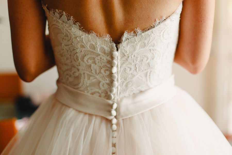 image shows the back details of a bride in her white wedding dress with buttons