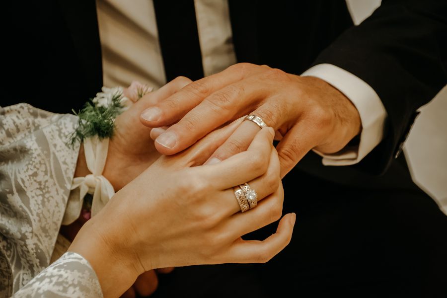 image shows a man and woman exchanging wedding rings