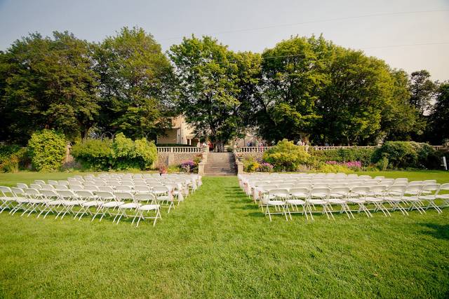 image shows white chairs set up on a green lawn for a wedding ceremony