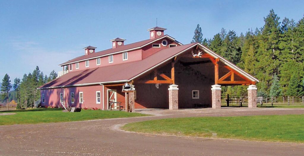 image shows a large red barn with large beautiful wooden beams